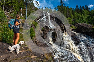 Elgafossen - Algafallet,  Backpacker girl with her dog looks at Waterfall Located between Sweden and Norway