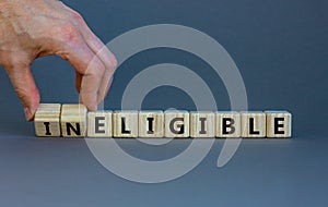 Eligible or ineligible symbol. Businessman turns wooden cubes and changes words Ineligible to Eligible. Beautiful grey table grey photo