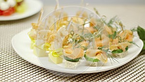 Elite catering, buffet reception of rare fish with capers and herbs. Media. White porcelain plate with small sandwiches