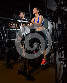 Elliptical walker trainer man and woman at black gym