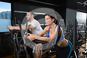Elliptical walker trainer man and woman at black gym
