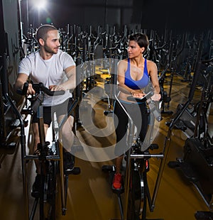 Elliptical walker trainer man and woman at black gym