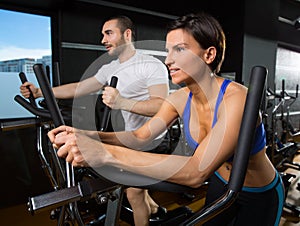 Elliptical walker trainer man and woman at black gym