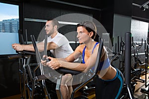 Elliptical walker trainer man and woman at black gym photo