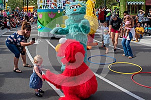 Elmo takes the hand of little girl in Sesame Street Party Parade at Seaworld.