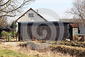 Elongated garage covered with dark corrugated metal protection in suburban family house backyard