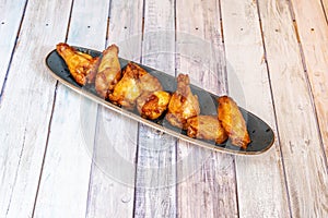 elongated tray with portion of fried chicken wings on the barbecue