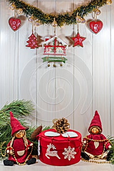 Elves, branches of a Christmas tree, New Year`s decor on a light wooden background. Close-up, vertical shot.