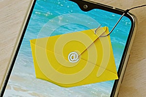 Email envelope caught with fishing hook on mobile phone - Phishing and mobile phone security concept