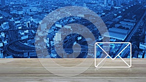 Email flat icon on wooden table over aerial view of modern city tower, street, expressway and skyscraper, Business contact us onli