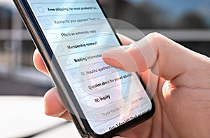 Email inbox in phone outdoors. List of new unread messages or spam mail. Marketing newsletters. Man looking at digital mobile.