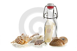 Email message in a bottle between sea shells isolated on white