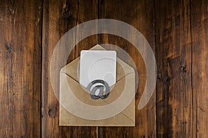 An email sign with white blank paper on a craft envelope lies on a vintage wooden table. Concept e-mail message letter. Top view