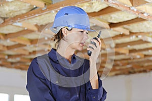 Emale inspector in helmet with walkie talkie in warehouse