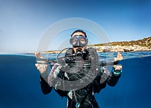 A emale scuba diver on the surface showing the OK sign