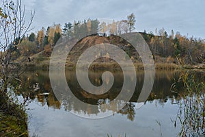 Embankment mountain with yellow-green forest reflected in water as if in mirror. Nature of Moscow region in autumn