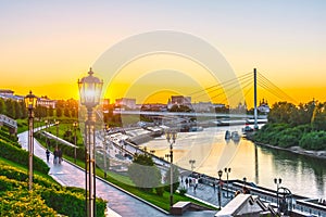 Embankment of the river with stairs and street lights at the summer sunset.