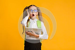 Embarassed Girl Clutching Head Using Tablet, Yellow Studio Background