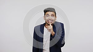 Embarrassed cheerful man showing shh sign holding finger near mouth, trying to keep secrets knowing private information