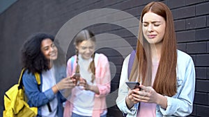 Embarrassed cyber bullying victim smartphone laughing students standing behind