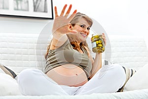 Embarrassed pregnant woman holding jar of pickles