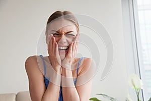 Embarrassed teen girl laughing holding hands on cheeks, headshot