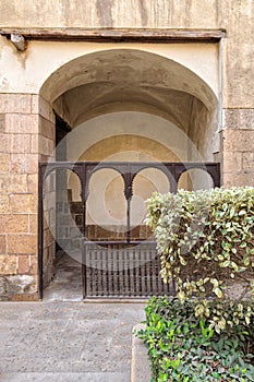 Embedded space with wooden balustrade and wooden arches behind a planted flower box at the external wall of an old historic house