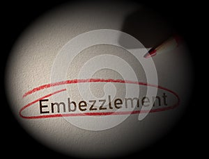 Embezzlement text circled in red pencil on dark background