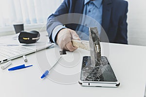 embittered businessman hits a smartphone with a hammer in workplace. Unsuccessful business negotiations concept. failure