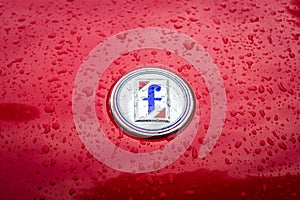 Emblem of the Italian carrozzeria Pininfarina on the Fiat 124 Sport Spider in raindrops.