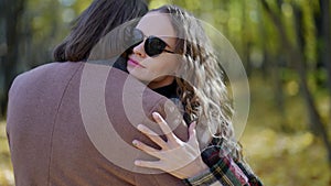 embrace of loving couple in autumn forest, woman is snuggling to her boyfriend