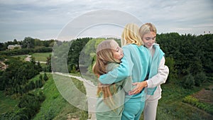 the embrace of three generations of women. An elderly woman hugs