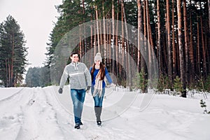 Embracing couple looking at camera with smiles in winter park. Winter walk