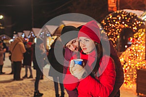 Embracing couple standing at Christams fair with a lot of lights