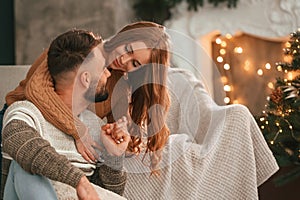 Embracing each other. Lovely young couple are celebrating New Year at home