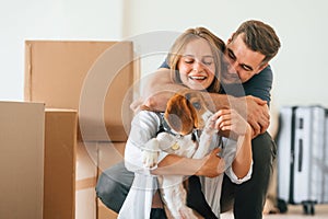 Embracing each other. Young couple with dog are moving to new home