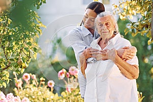 Embracing and smiling. Young woman is with her senior mother is in the garden