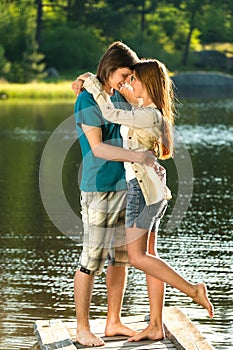 Embracing teens standing barefoot on pier