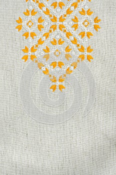 Embroidered fragment on flax by yellow and white cotton threads. Macro embroidery texture flat stitch.