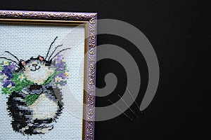 Embroidered striped grey fat cat with a bouquet of violet flowers on a white canvas. Metal embroidery needles.