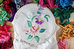 embroidery hoop with floral embroidery. floss threads around. top view