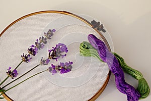 Embroidery hoop with lavender flowers and purple and green floss closeup.