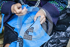 Embroidery with patterns on clothes close-up, woman`s hands embroidering a pattern on fabric