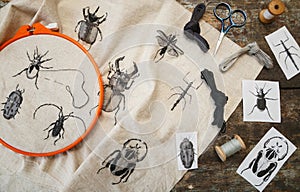 Embroidery in process with hoop and sewing threads on table.