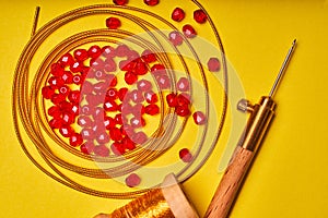 Embroidery products and tools. Luneville hook and red roundels on a yellow background