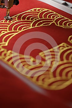 Embroidery of traditional shell pattern and stitched pig outline with gold on red fabric - chinese new year concept