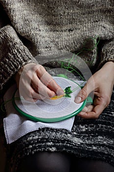 Embroidery in woman hands, female doing flower pattern embroidery on grandma natural clothes