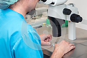 Embryologist or lab technician adjusting needle to fertilize a human egg under the microscope. Doctor adding sperm to egg using mi