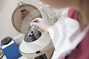 Embryologist putting sample into centrifuge photo