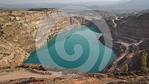 Emerald Azure lake in a flooded quarry in the shape of a heart. Oval lake in mining industrial crater, acid mine